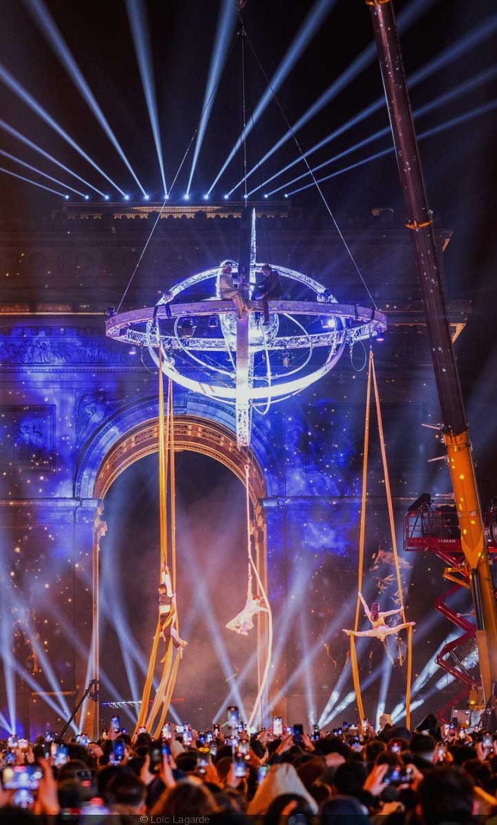 Spectacle lumineux avec des effets visuels marquants et des acrobates suspendus.