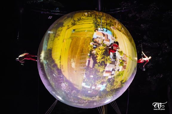 Deux artistes de cirque évoluent à l'intérieur d'une grande bulle transparente.