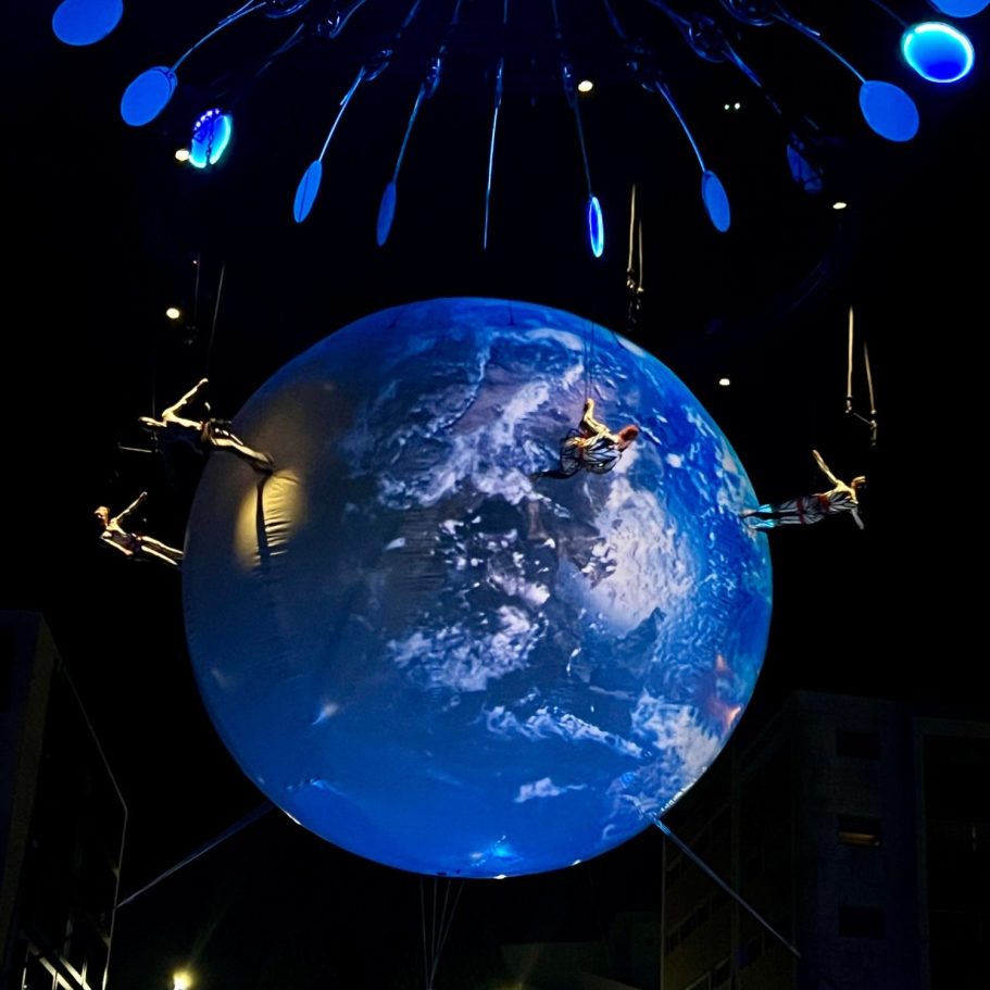 Globe stylisé projetant des images de la Terre, suspendu avec des éléments lumineux.