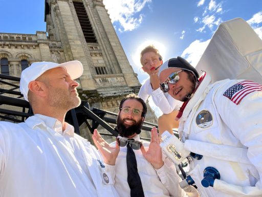 Groupe de quatre personnes en dehors d'un bâtiment, dont un astronaute et un enfant.