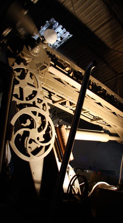 Machine ancienne avec rouages, visible dans un éclairage tamisé.