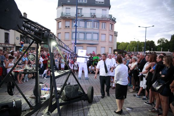 Spectacle de rue avec un public devant un artiste en costume éclairé.