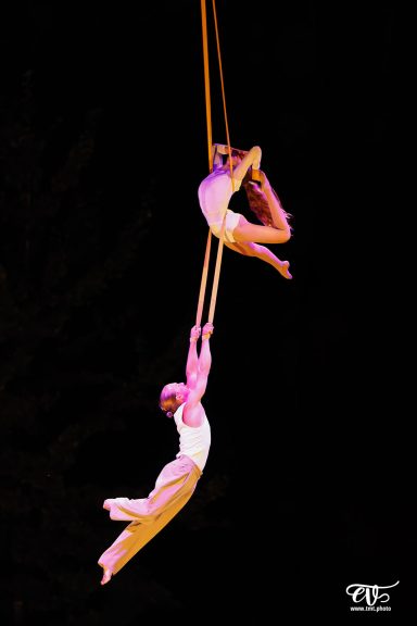 Deux artistes suspendus dans les airs, exécutant une performance acrobatique.