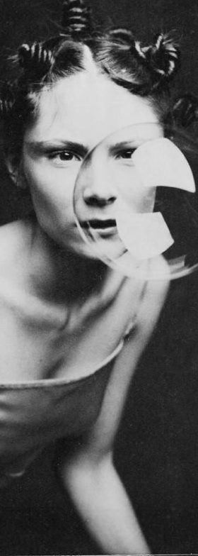 Femme avec une expression intense, des boucles et un décor minimaliste en noir et blanc.