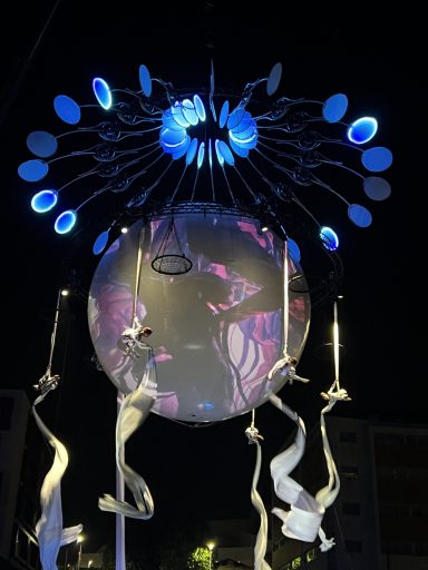 Installation artistique lumineuse avec projections et motifs colorés au centre.