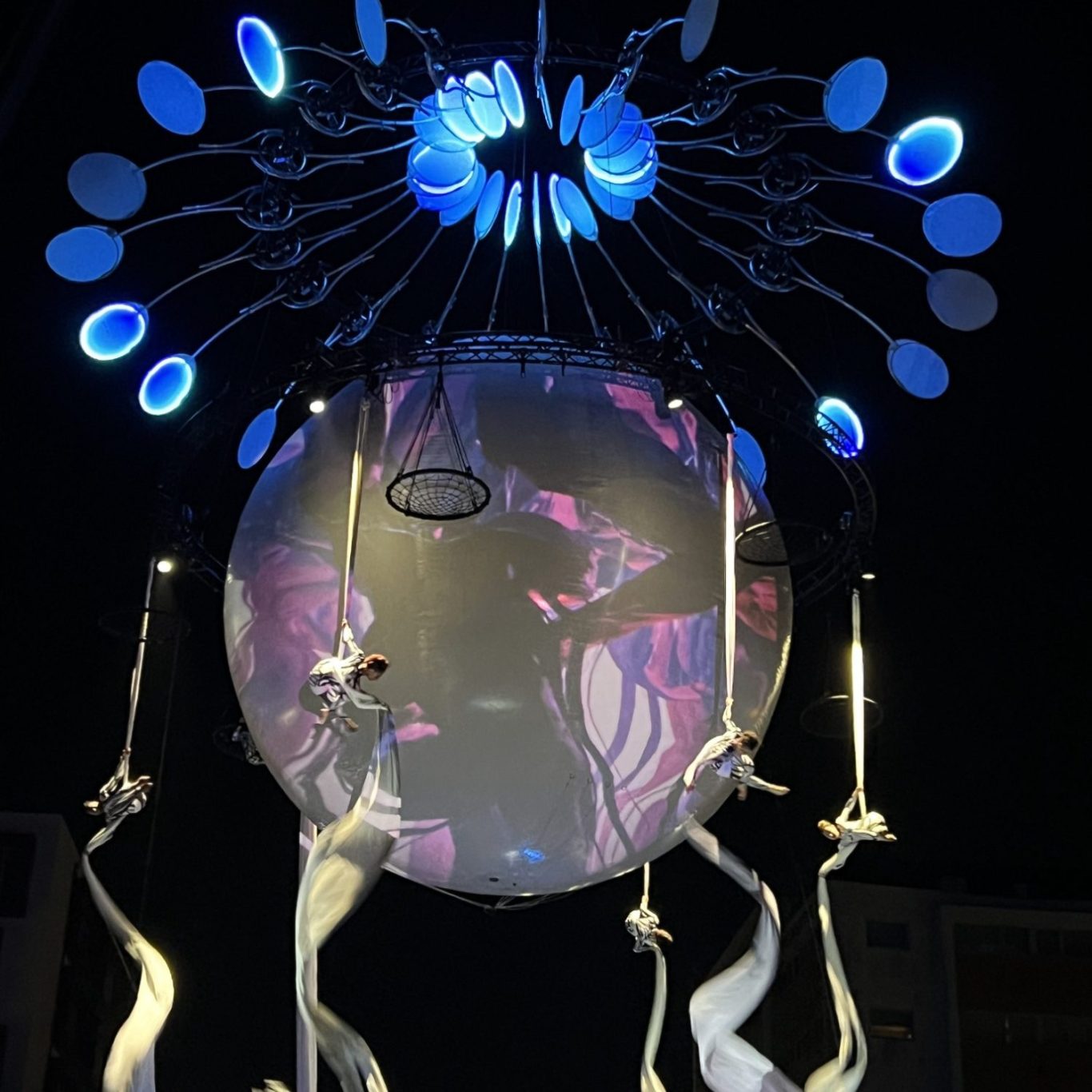 Deux artistes acrobates suspendus dans les airs, manipulant des tissus blancs.