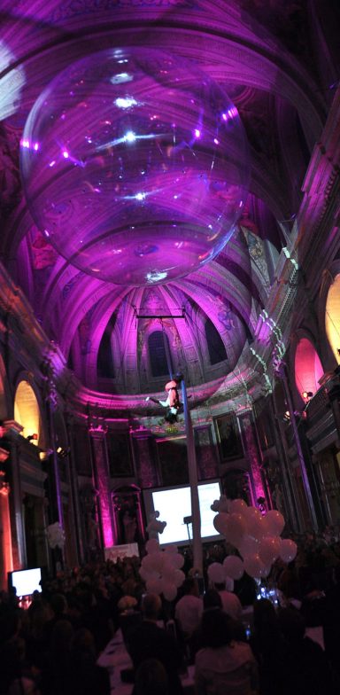 Salon élégant avec un plafond voûté illuminé en violet, entouré de personnes en fête.