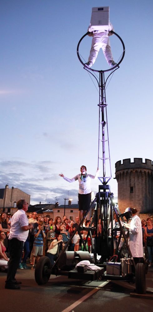 Artiste acrobatique sur une structure mécanique, silhouetté contre le ciel au crépuscule.