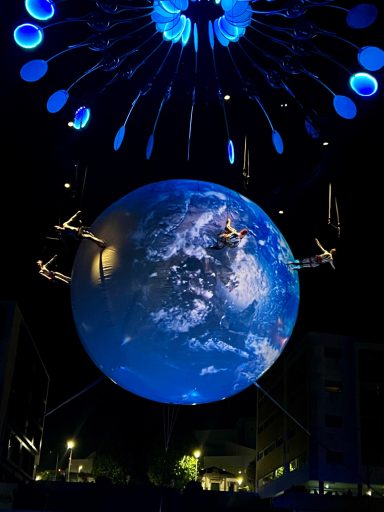 Globe lumineux représentant la Terre, suspendu avec des éléments lumineux au-dessus.