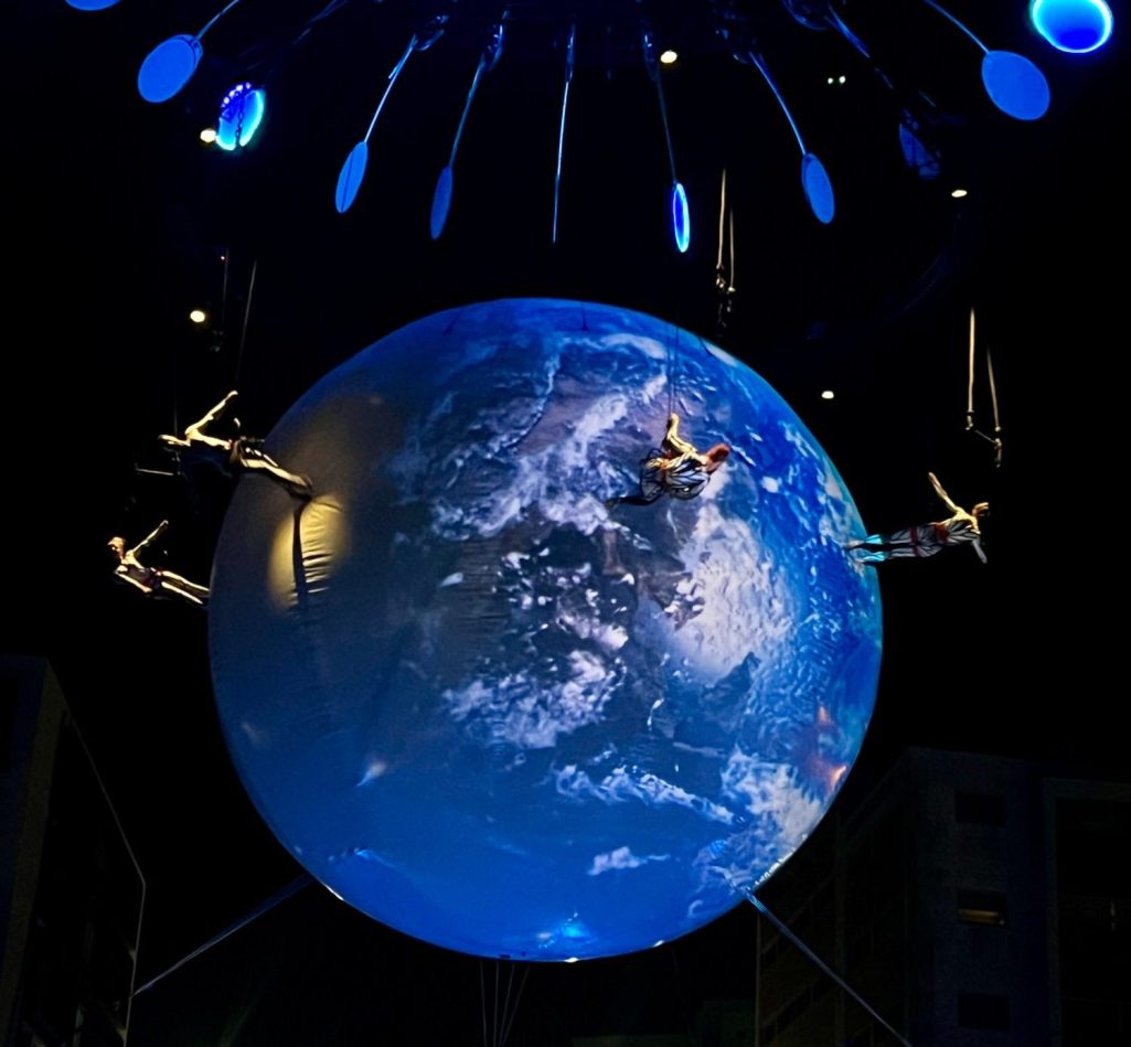 Planète terrestre illuminée, suspendue dans les airs avec des figures acrobatiques.