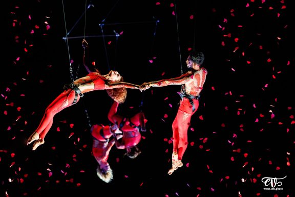 Trois artistes acrobates enroulés dans des performances aériennes, suspendus par des cordes.