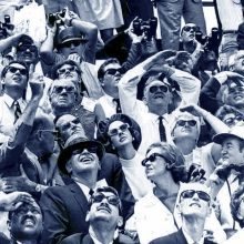 Groupe de personnes en costume regardant vers le ciel, lunettes de soleil sur le visage.