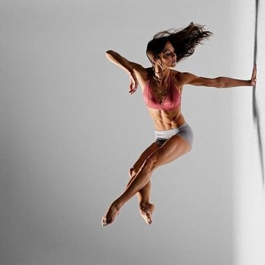Danseuse en plein saut, vêtue d'un soutien-gorge rose et culotte, tournant vers la droite.