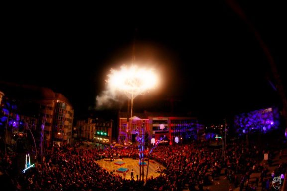 Salle de concert illuminée avec un feu d'artifice au-dessus d'un public enthousiaste.