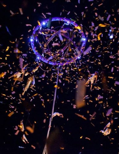 Des éclats colorés tourbillonnent autour d'un cerceau lumineux suspendu.