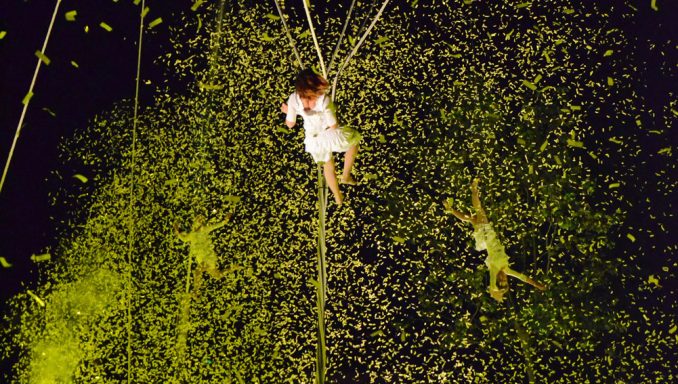 Une personne suspendue dans les airs, entourée de confettis colorés.