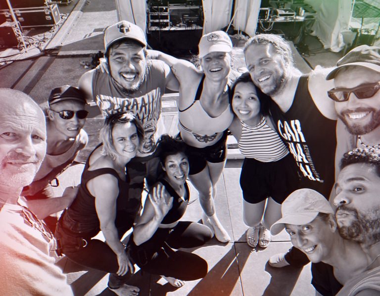 Groupe de dix personnes souriantes, posant ensemble sur un bateau au soleil.