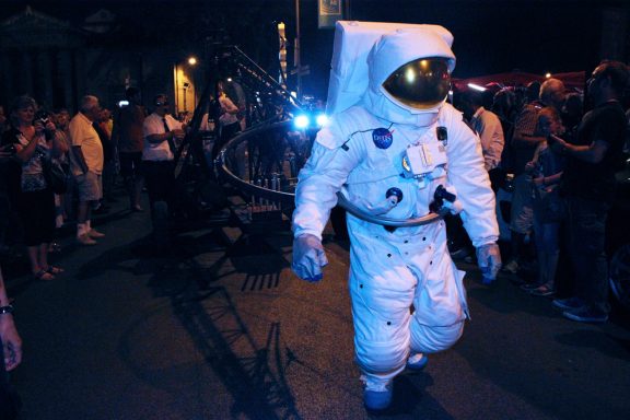 Un astronaute en combinaison marche parmi une foule lors d'un événement nocturne.