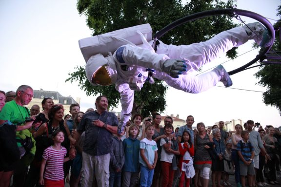 Un astronaute en apesanteur, entouré d'une foule admirative.