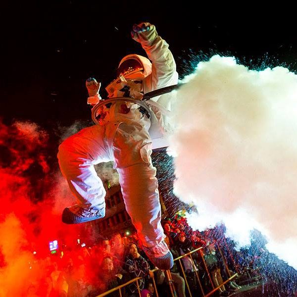 Astronaute en combinaison, sautant avec des effets de fumée colorée autour de lui.