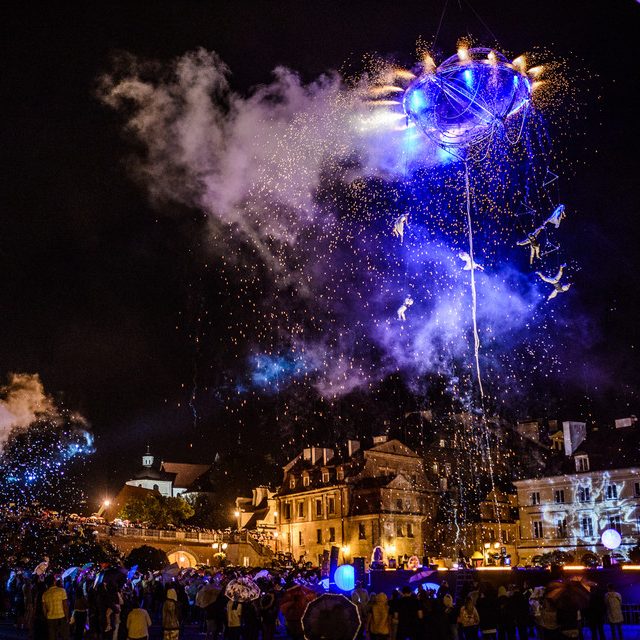 Spectacle nocturne avec feux d'artifice et foule illuminée.