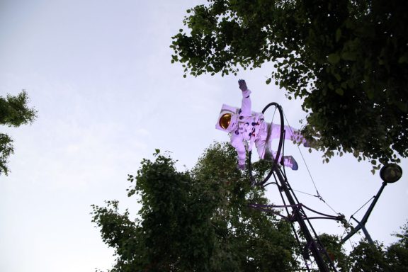 Un astronaute en costume flottant parmi les arbres sous un ciel clair.