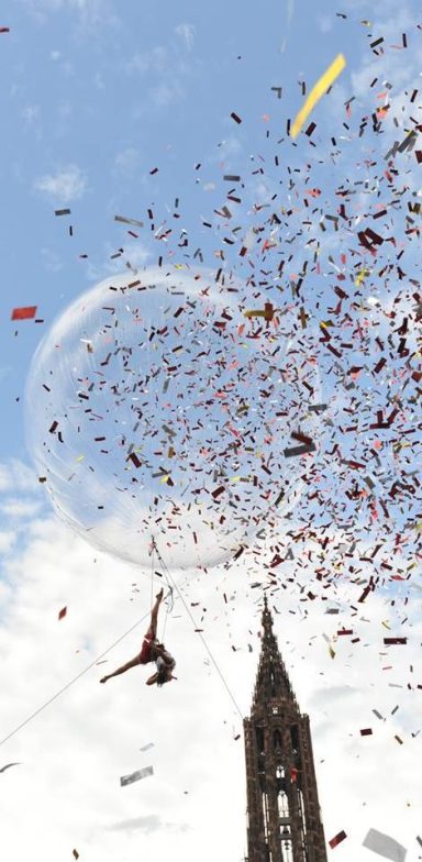 Destruction de confettis colorés au-dessus d'une tour, ciel bleu en arrière-plan.