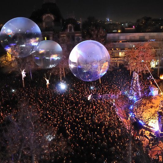 Foule massée sous des sphères transparentes lors d'un événement nocturne.