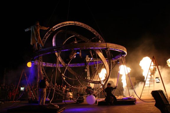 Spectacle de feu avec des artistes sur scène devant un public enthousiaste.