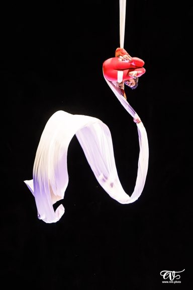 Nœud de tissu suspendu, enroulé, de couleur blanche sur fond sombre.